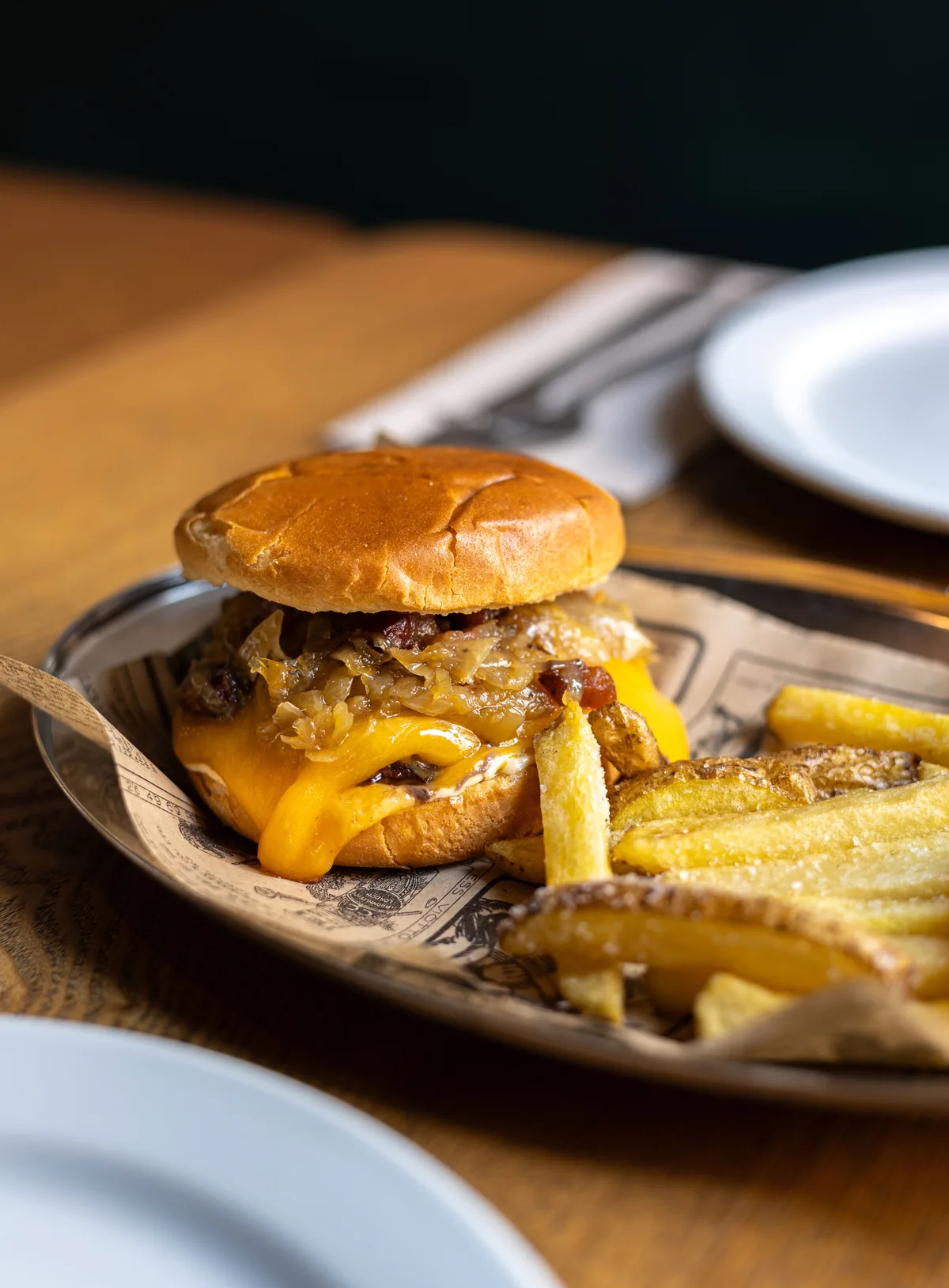Cheeseburger with melted cheddar and fries served on a lined metal tray