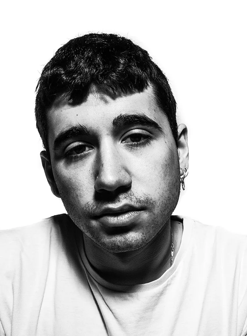 Young man with cropped hair and a white t-shirt facing the camera in flat, high-key light
