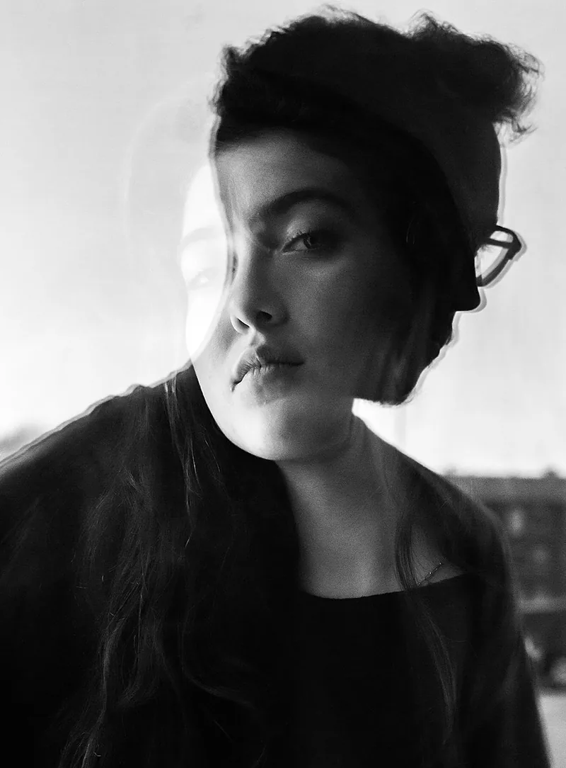 Young woman with her hair pinned up turning towards the camera behind a pane of glass